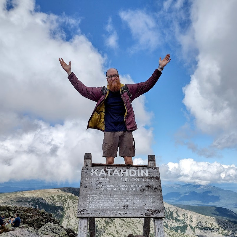 Standing on top of the summit sign on Mt. Katahdin